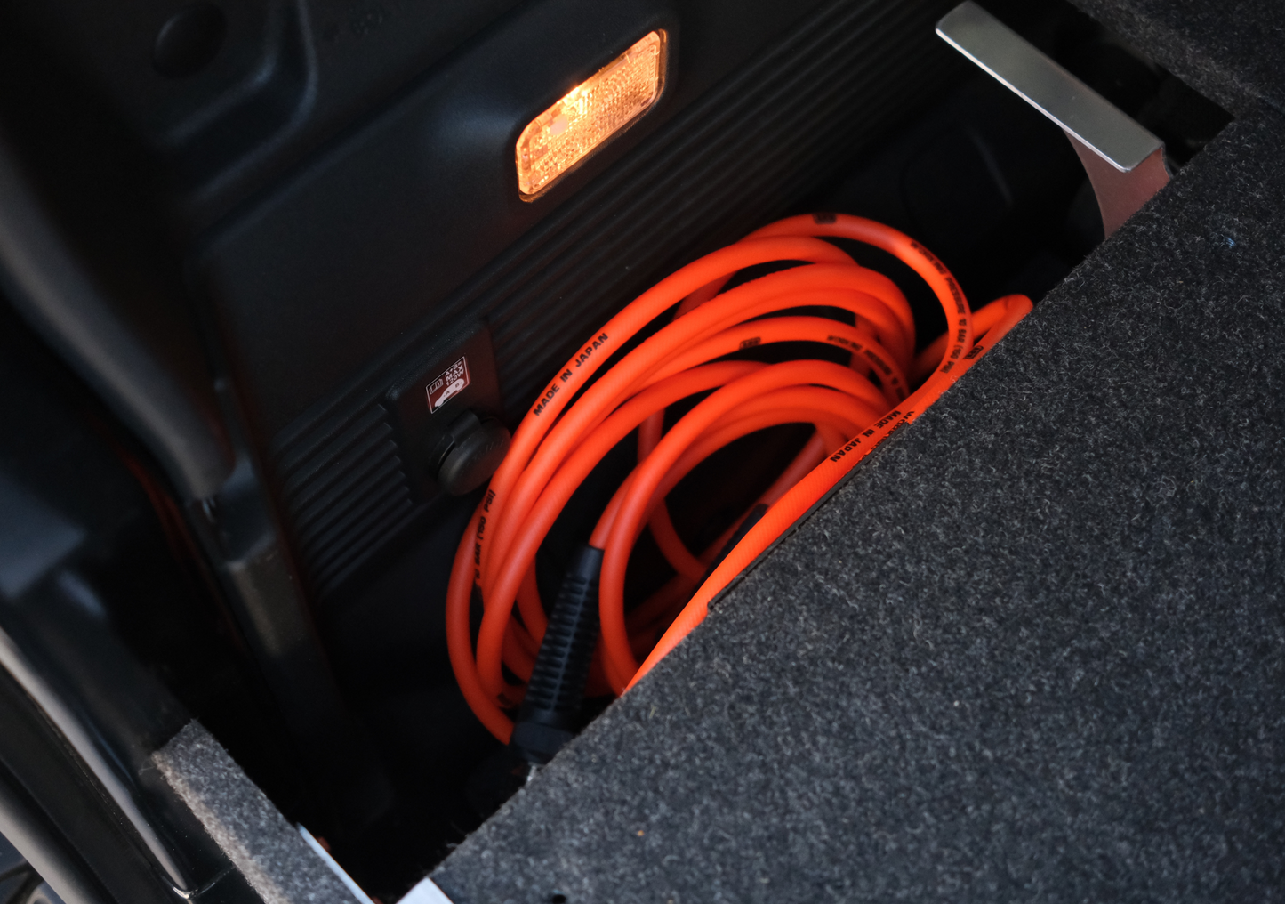 Orange coiled cable stored inside the jimny xl drawer system with black interior and built-in light