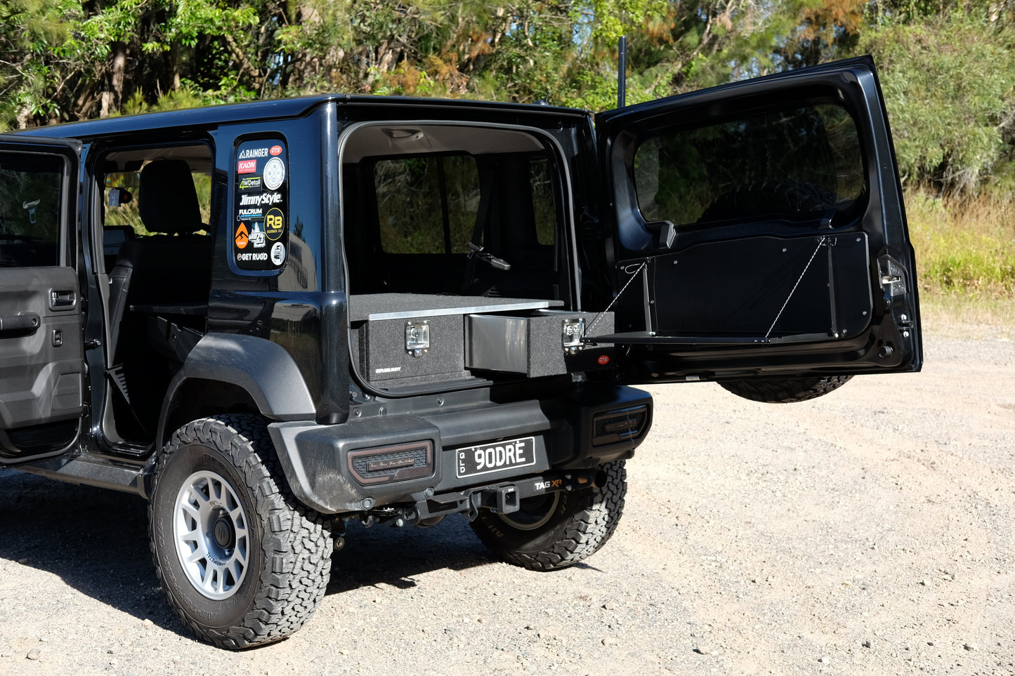 Suzuki Jimny with Suzuki Jimny XL Drawer System and Wing Kit installed on open rear door in outdoor setting